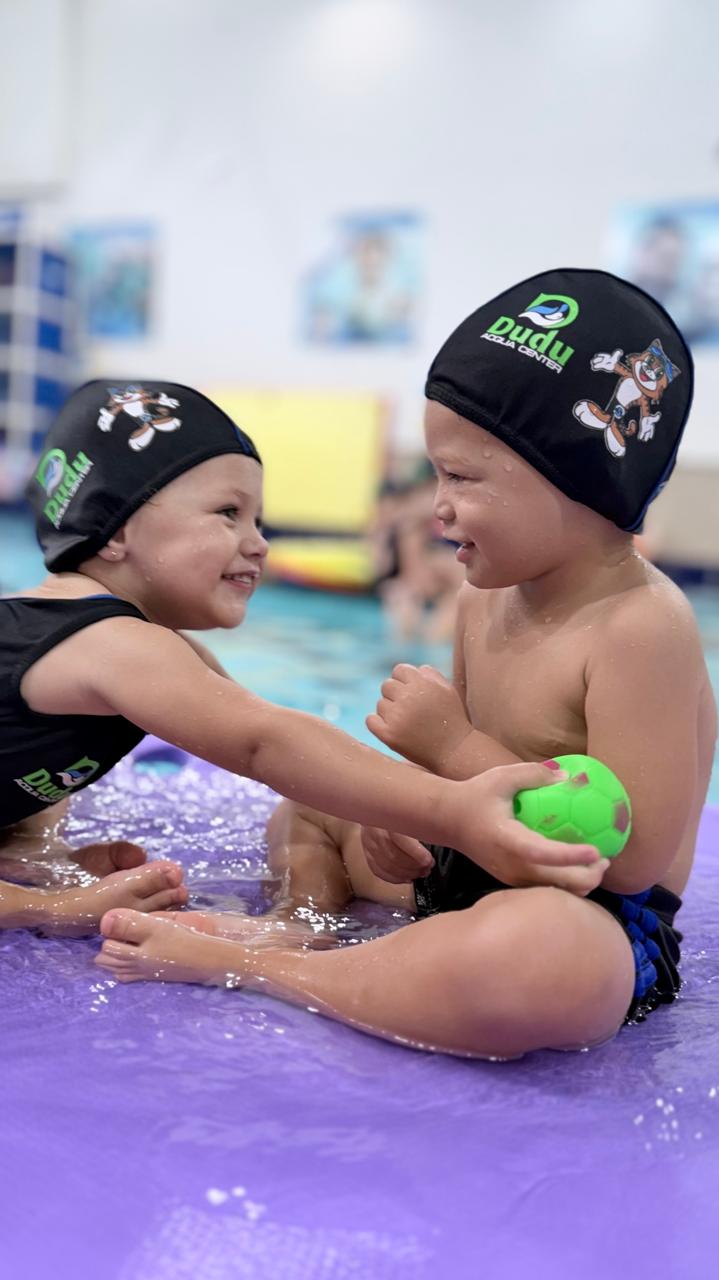 Bebês brincando com bola na piscina